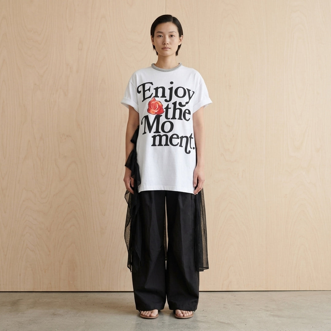 White oversized cotton tee dress with 'Enjoy the Moment' black lettering and a red rose graphic, crystal-embellished neckline and sheer black chiffon ruffle layers - lifestyle