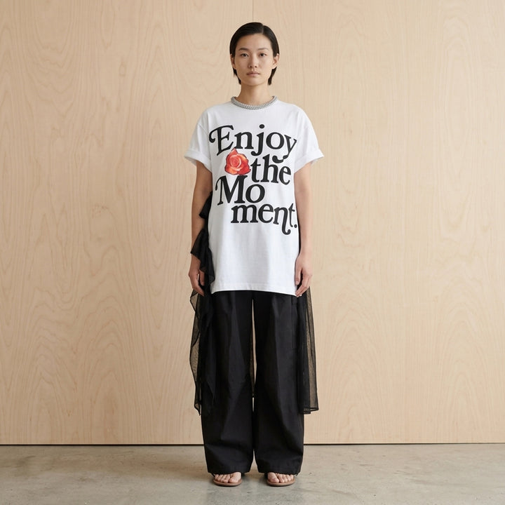 White oversized cotton tee dress with 'Enjoy the Moment' black lettering and a red rose graphic, crystal-embellished neckline and sheer black chiffon ruffle layers - lifestyle