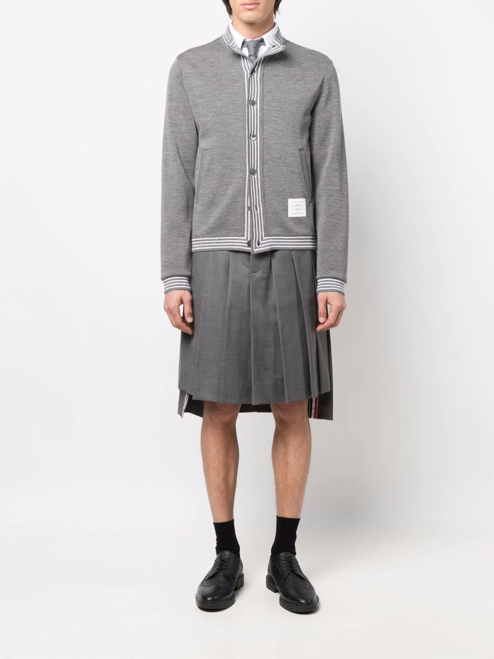 Thom Browne Classic Rise Pleated Knee Length Skirt in medium grey wool with RWB grosgrain ribbon trim at the hem, front view on white background.