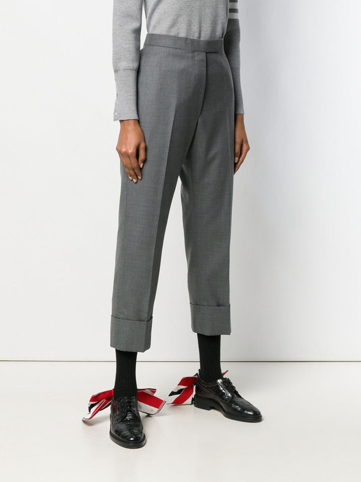 Thom Browne Classic Backstrap Trouser in medium grey wool with high waist, pressed creases, and wide turn-up cuffs, flat lay on white background