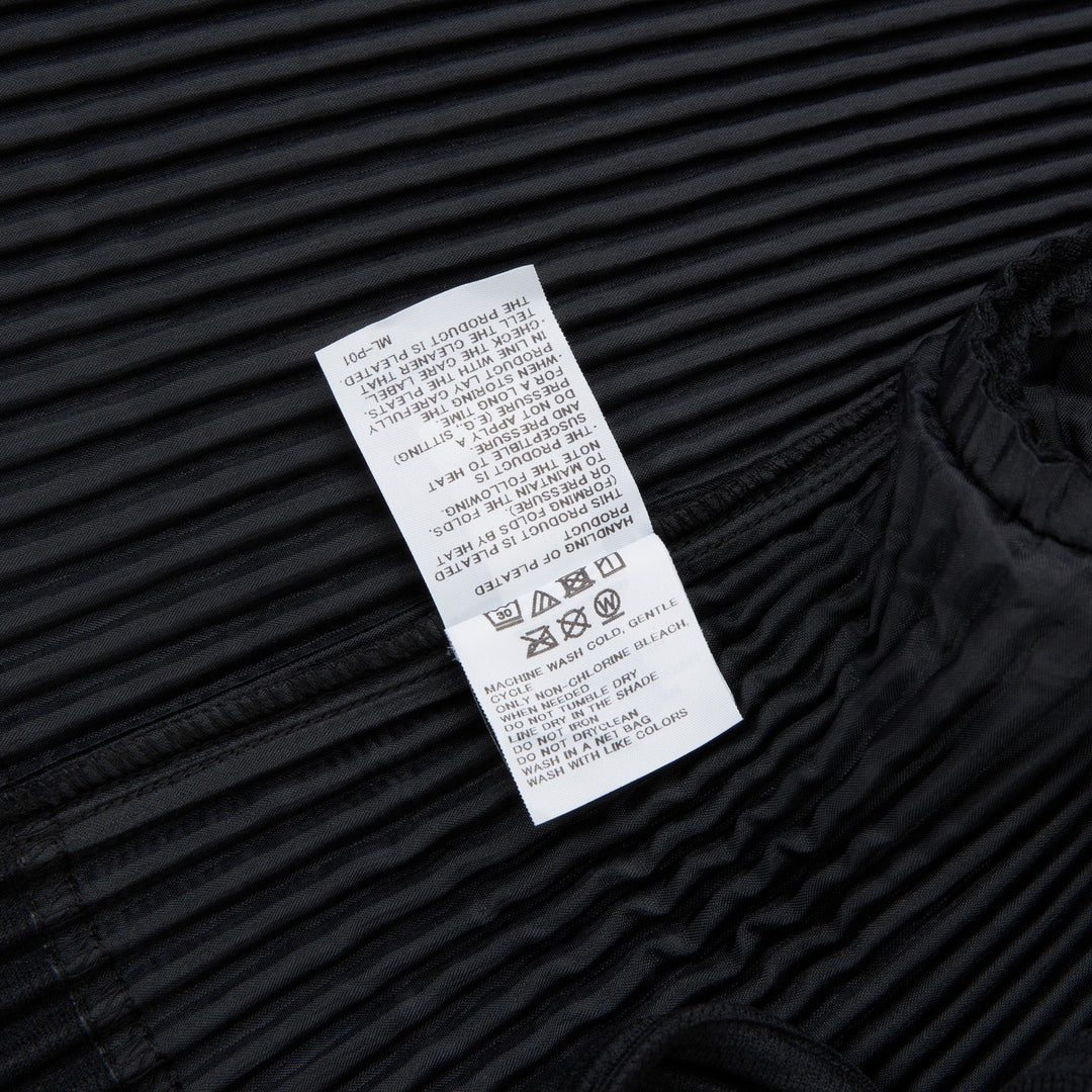 Homme Plissé Issey Miyake black pleated two-button blazer with notched lapels and all-over vertical pleated texture, front view on white background