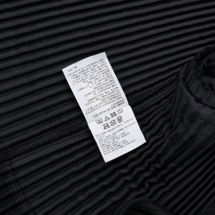 Homme Plissé Issey Miyake black pleated two-button blazer with notched lapels and all-over vertical pleated texture, front view on white background