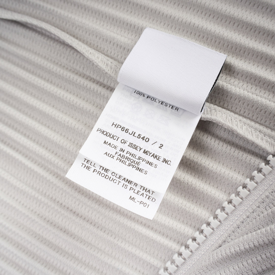 Homme Plissé Issey Miyake Basics Zip-Up Cardigan in light grey with all-over steam pleating, funnel neck, and full-length tonal zip, displayed flat on white background - view 3