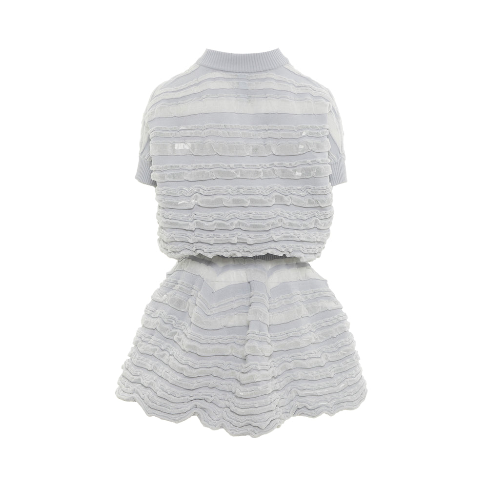 CFCL Swell Glitter Puff two-piece set in pale grey featuring horizontal ruffled puff tiers with glitter shimmer, short sleeve crop top with mock neck, and matching mini skirt