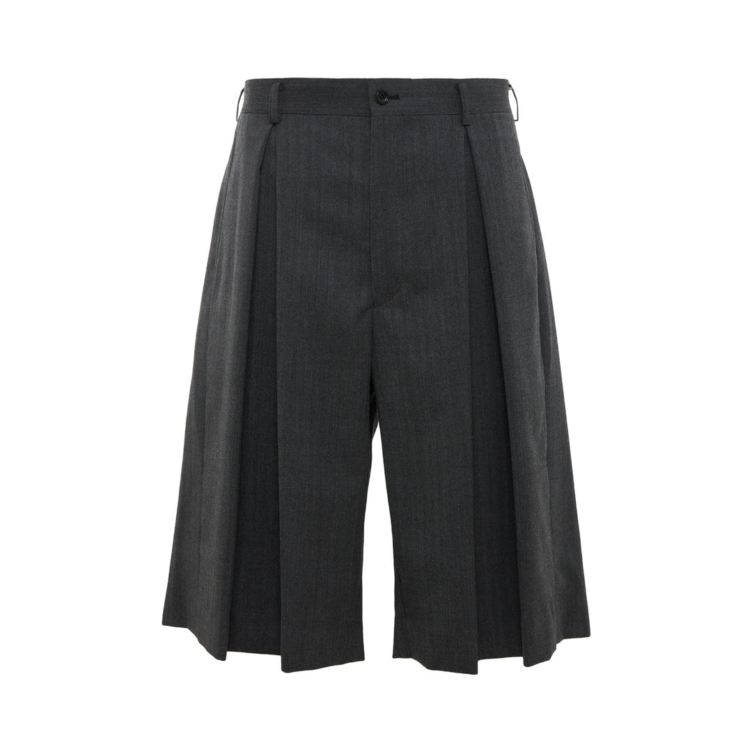 COMME des GARCONS HOMME PLUS Pleated Wide-Leg Shorts in charcoal grey with deep forward pleats and high-rise waistband, front view on white background