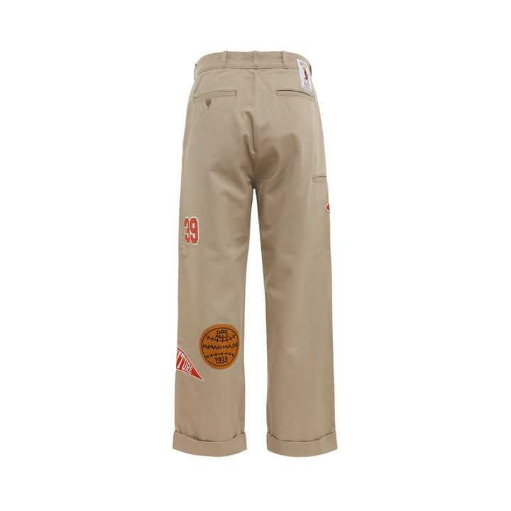 Human Made College Patch Pants in khaki with embroidered varsity patches and chenille H logo on straight-leg cuffed chinos