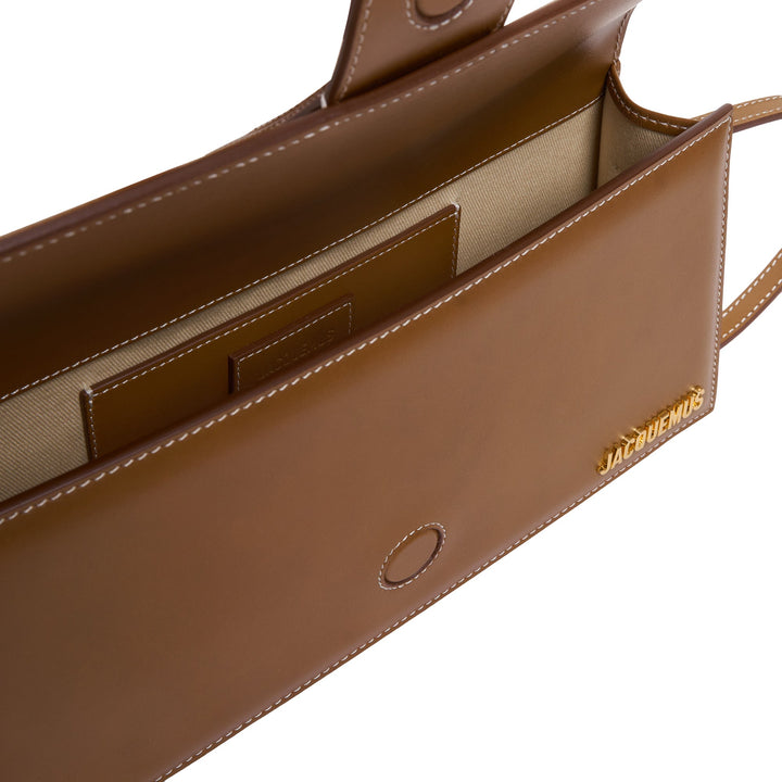 JACQUEMUS Le Bambino Long shoulder bag in tan smooth leather with white contrast stitching, central tab closure, and gold logo lettering