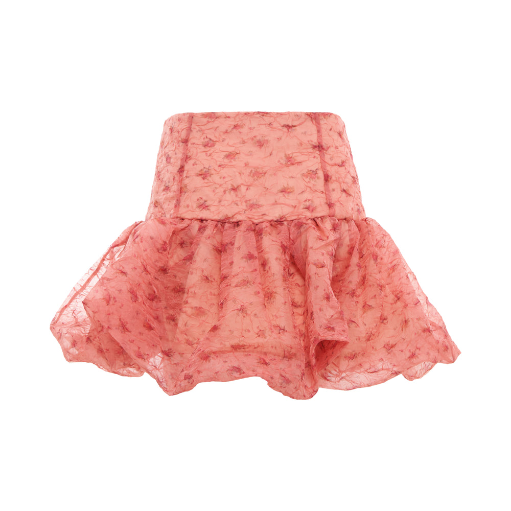 Ganni Shibori Organza Mini Skirt in coral pink with dark floral print, featuring a high waist and gathered ruffle hem, displayed flat on white background