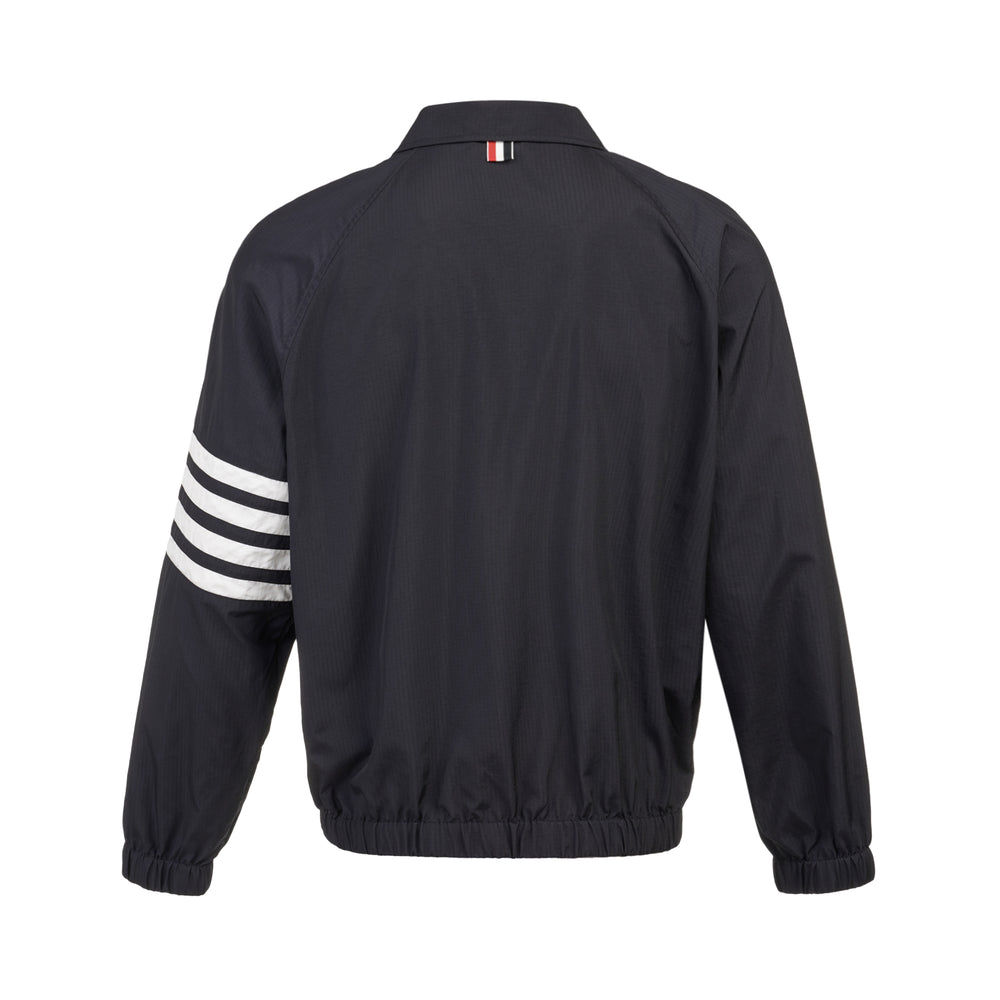 Thom Browne navy zip-front raglan coach jacket with signature four-bar white and black stripe across the sleeve, spread collar, and elasticated hem, on a white background - view 2