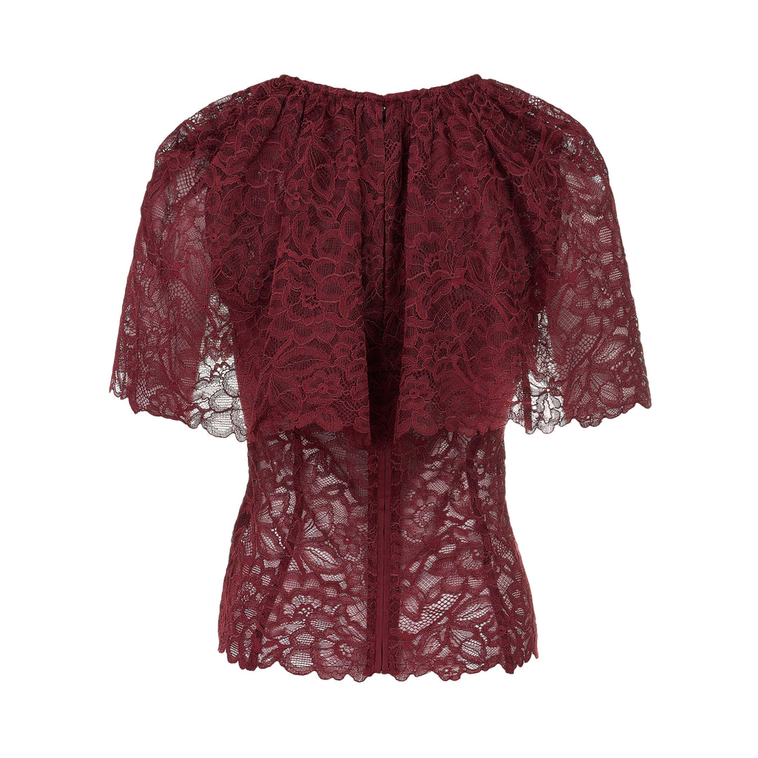 Self-Portrait burgundy floral lace cape top with gathered neckline, draped cape overlay, scalloped edges, and concealed back zip — rear view on white background