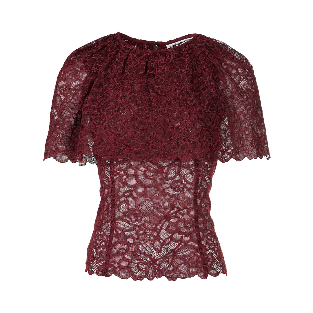 Self-Portrait burgundy floral lace cape top with gathered neckline, draped cape overlay, scalloped edges, and concealed back zip — rear view on white background