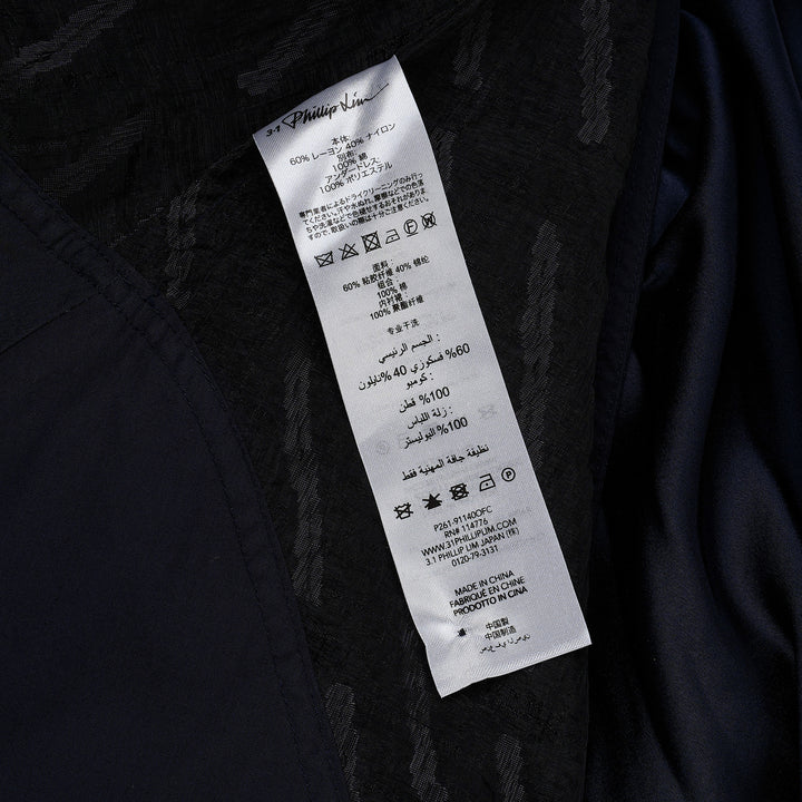 3.1 Phillip Lim black textured organza belted tulip dress with cap sleeves, D-ring navy belt, and contrast navy hem border, photographed on a white background