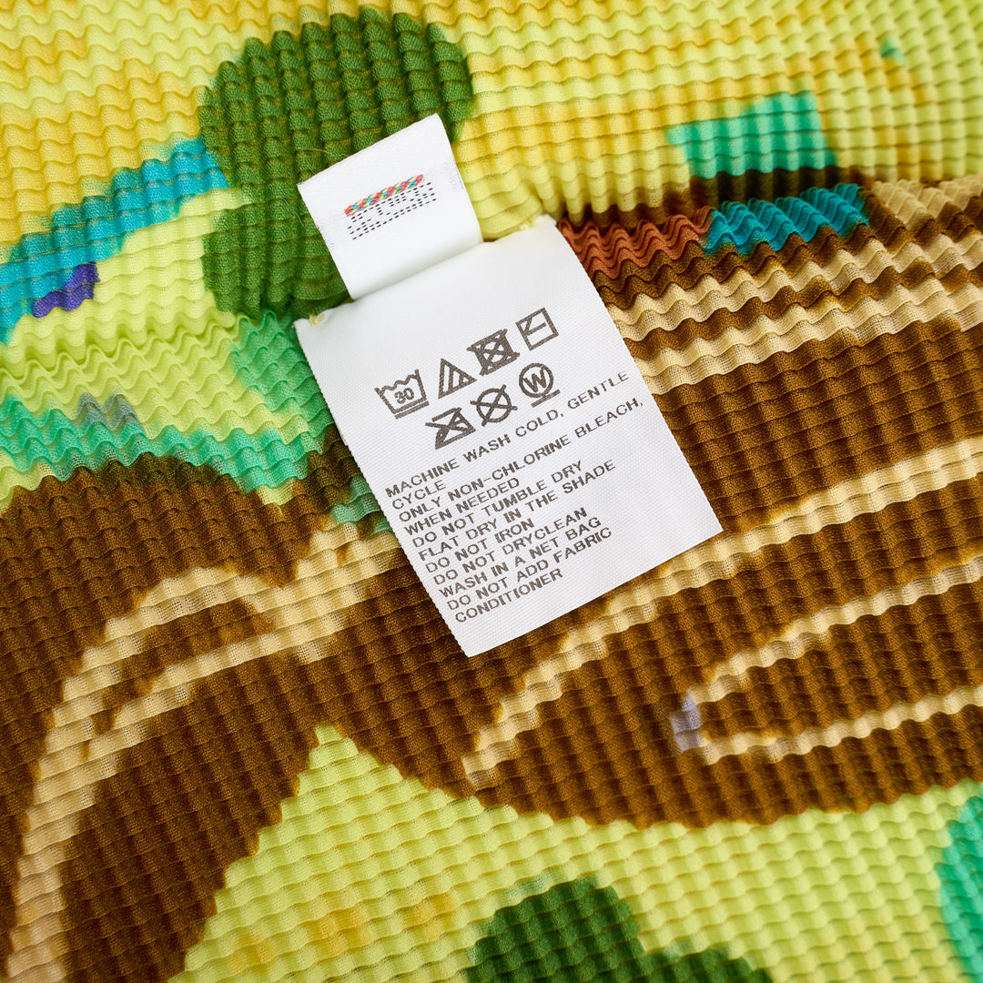 me Issey Miyake Island Print High Neck Top in neon yellow-green with all-over tropical graphic featuring monkeys, palm fronds, and swirling teal brushstrokes in fine-pleat fabric, short cap sleeves, mock-neck collar - view 4
