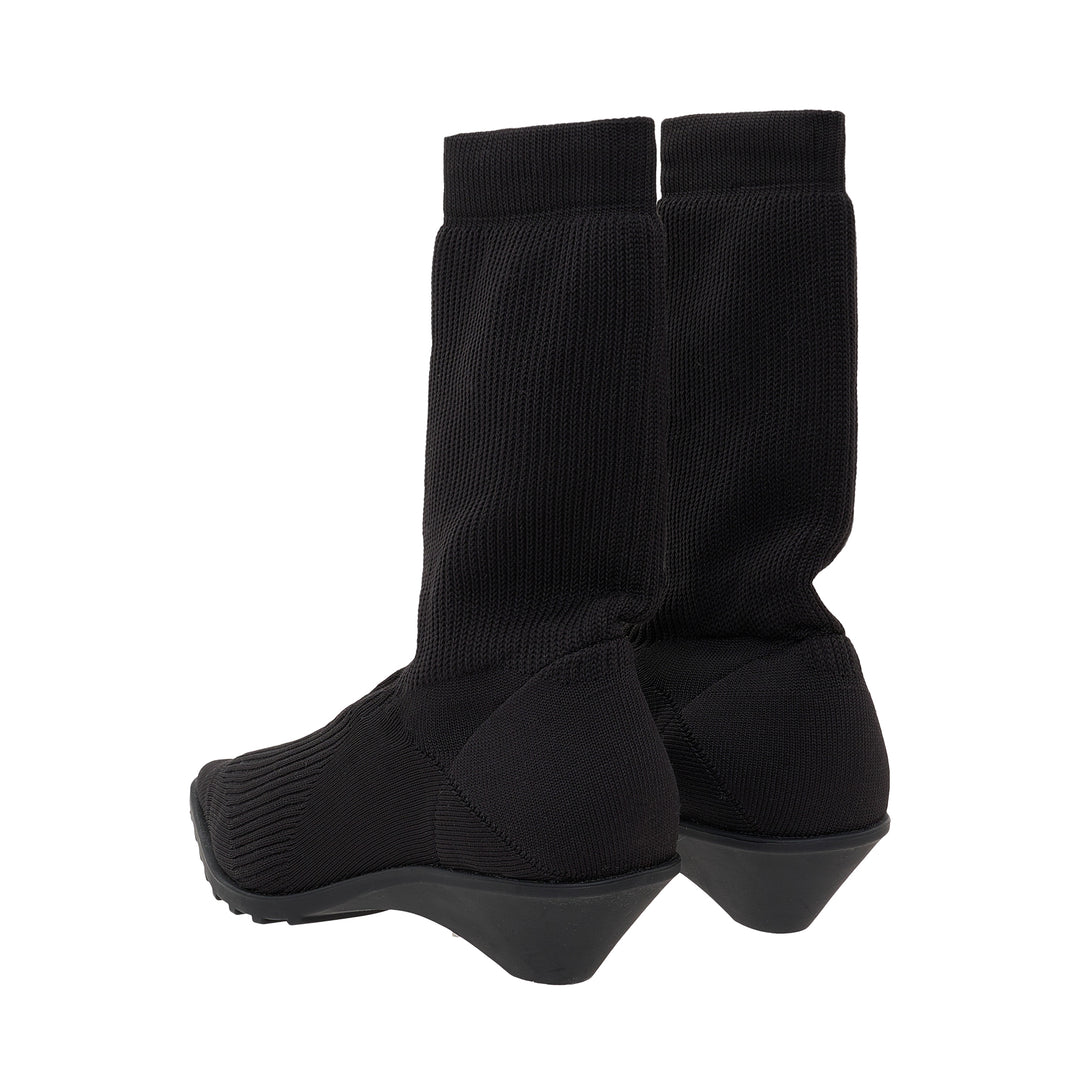 Issey Miyake black fine-gauge ribbed knit sock boot with a pointed toe, star-motif panel at the vamp, and sculptural moulded wedge sole, shown in profile against a white background - view 3