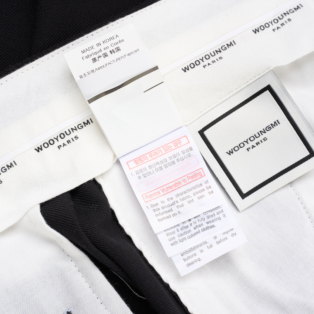 Wooyoungmi black pleated high-rise trousers with double front pleats and side metal buckle adjuster, displayed flat on white background - view 5