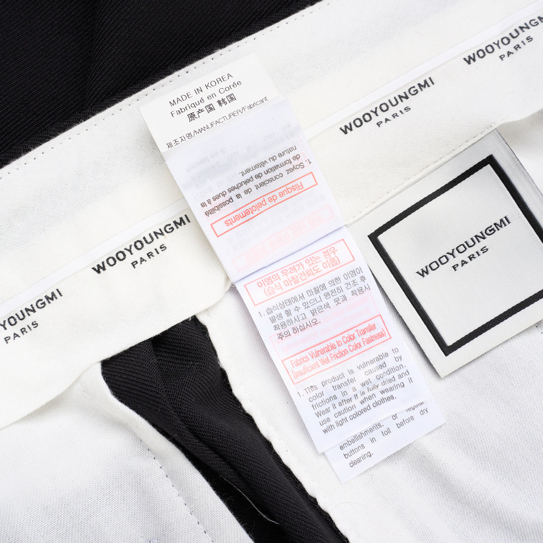 Wooyoungmi black pleated high-rise trousers with double front pleats and side metal buckle adjuster, displayed flat on white background - view 6