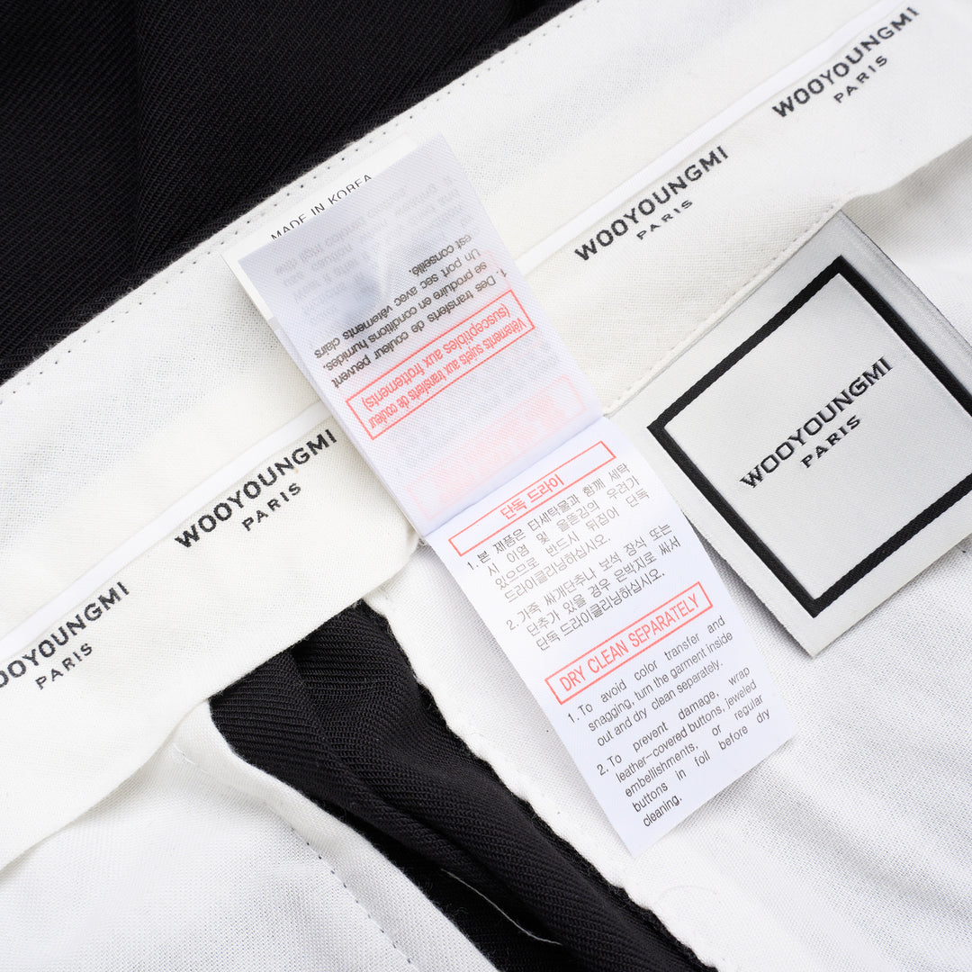 Wooyoungmi black pleated high-rise trousers with double front pleats and side metal buckle adjuster, displayed flat on white background - view 7