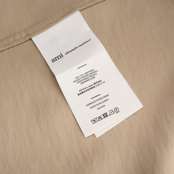 AMI Alexandre Mattiussi Shark Collar Boxy Short Sleeve Shirt in tan and black with contrast cream piping and button-through front, flat lay on white background - view 3