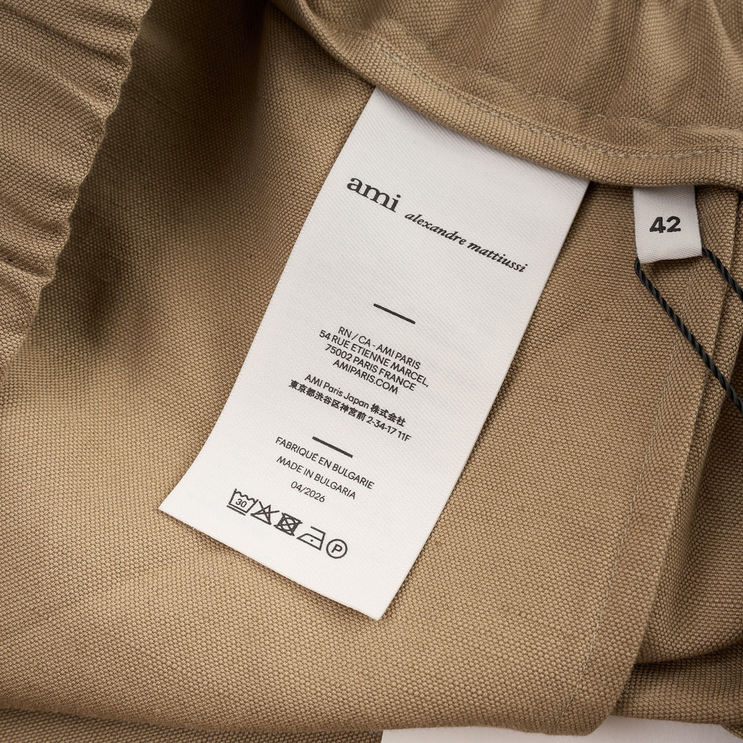 AMI Elasticated Large Bermuda Shorts in khaki tan, featuring a wide-leg silhouette, elasticated paper-bag waistband with drawstring, and hem side slits, displayed flat on a white background - view 3
