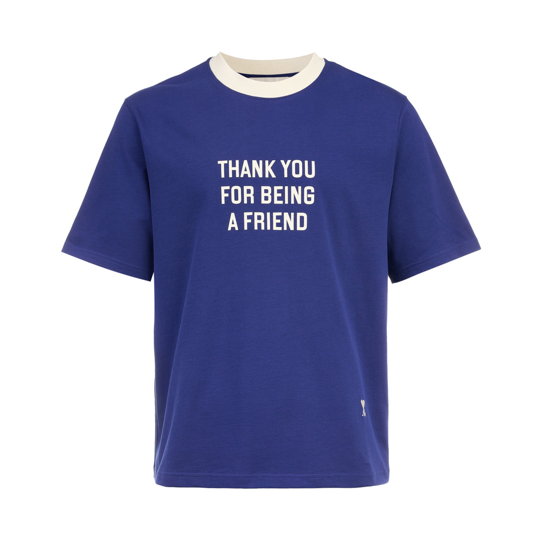 AMI royal blue cotton graphic T-shirt with 'Thank You For Being A Friend' slogan print in cream lettering, featuring a contrast cream ribbed crew neckline and AMI de Cœur logo at the hem