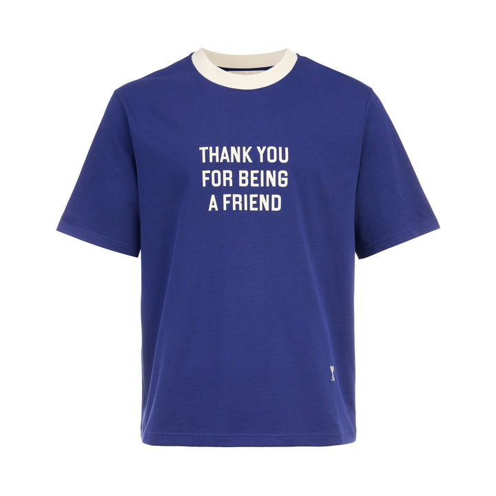 AMI royal blue cotton graphic T-shirt with 'Thank You For Being A Friend' slogan print in cream lettering, featuring a contrast cream ribbed crew neckline and AMI de Cœur logo at the hem