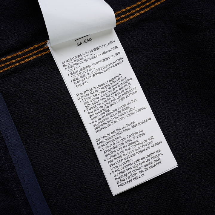 sacai indigo denim trucker jacket with contrast topstitching, pleated front panels, button-flap chest pockets and a layered hem, shown from the front - view 5