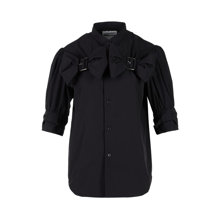 Noir Kei Ninomiya black button-up shirt with band collar, oversized bow with buckle straps across the chest and puffed elbow-length sleeves