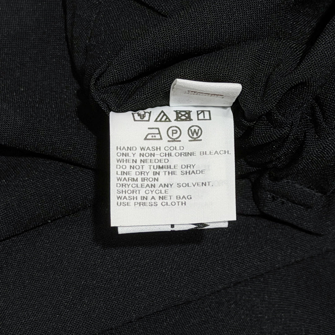 132 5. Issey Miyake Seamless Basic Woven Pants in black, featuring a wide-leg silhouette, wrap-style front panel, and dual drawstring and button waistband