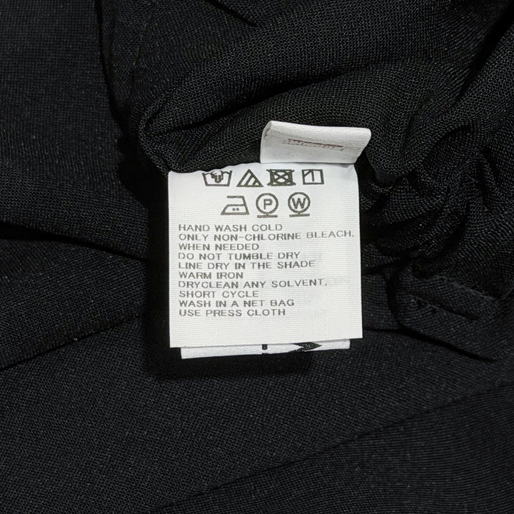132 5. Issey Miyake Seamless Basic Woven Pants in black, featuring a wide-leg silhouette, wrap-style front panel, and dual drawstring and button waistband
