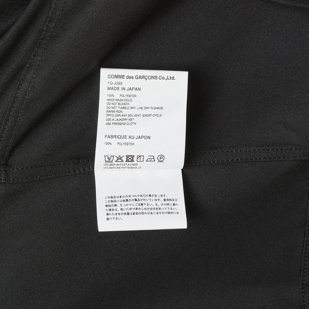 Comme des Garçons BLACK sleeveless off-center jacket in black with asymmetric hem, button front, and dual chest flap pockets