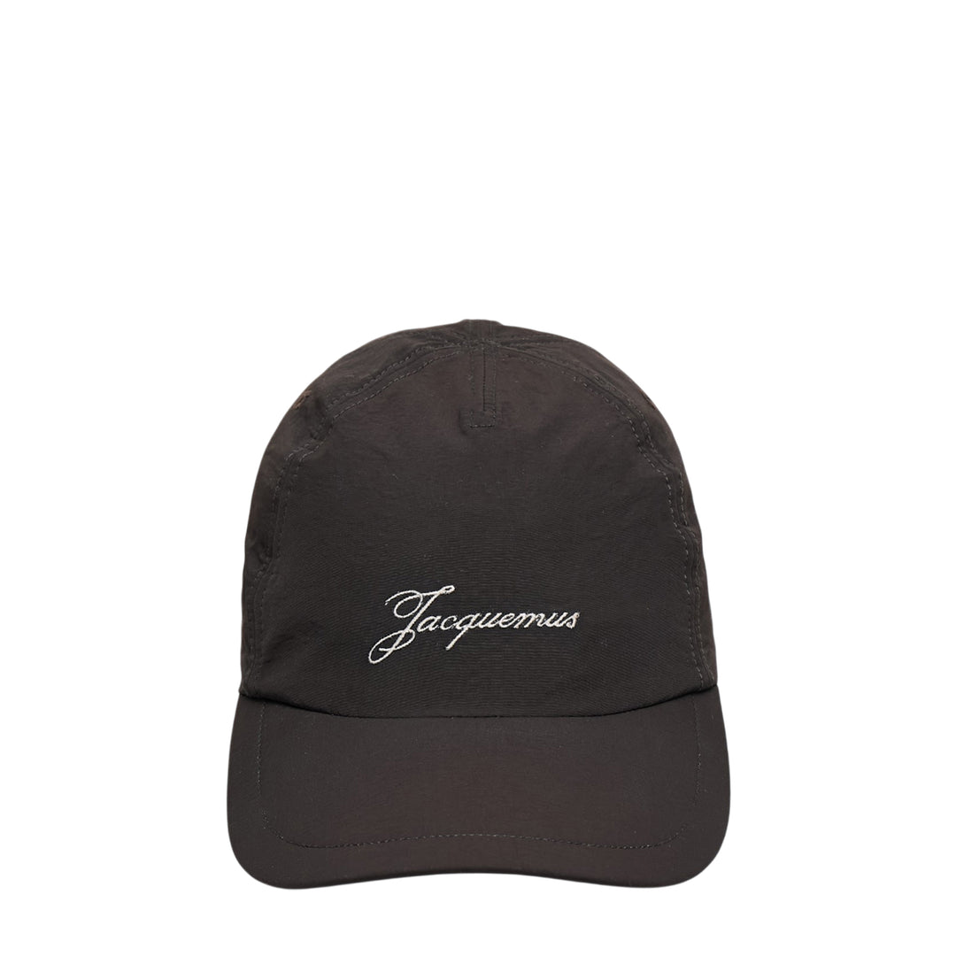 Jacquemus La Casquette Baluchon dark baseball cap with white script logo embroidery on the front panel, front view