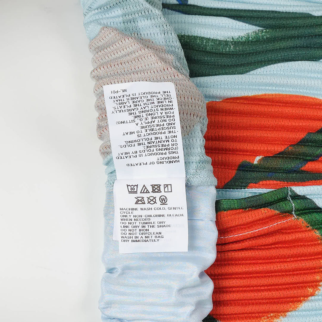 Homme Plissé Issey Miyake Fruits & Vegetables Pleated Shorts in light blue with orange citrus and green leaf all-over print, back view