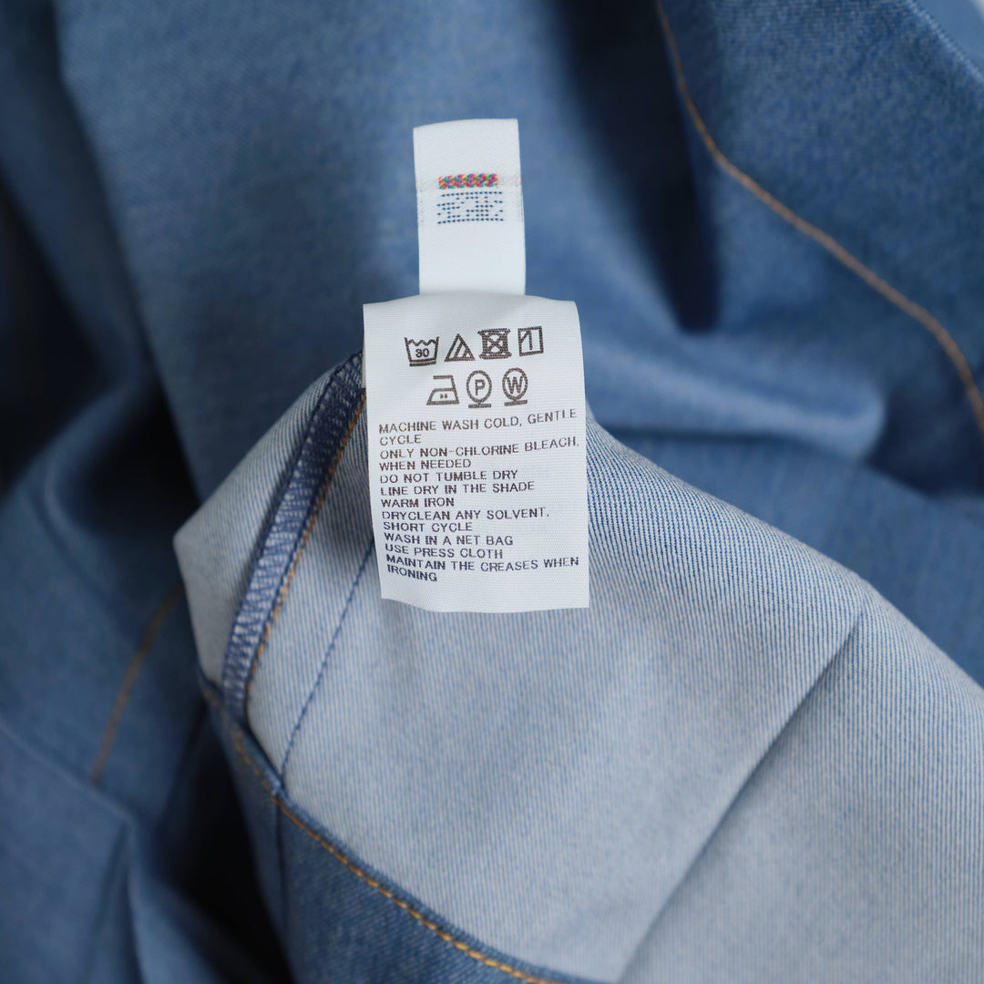 me Issey Miyake Flat Denim Jacket in light blue with purple buttons and contrast gold topstitching, flat lay front view
