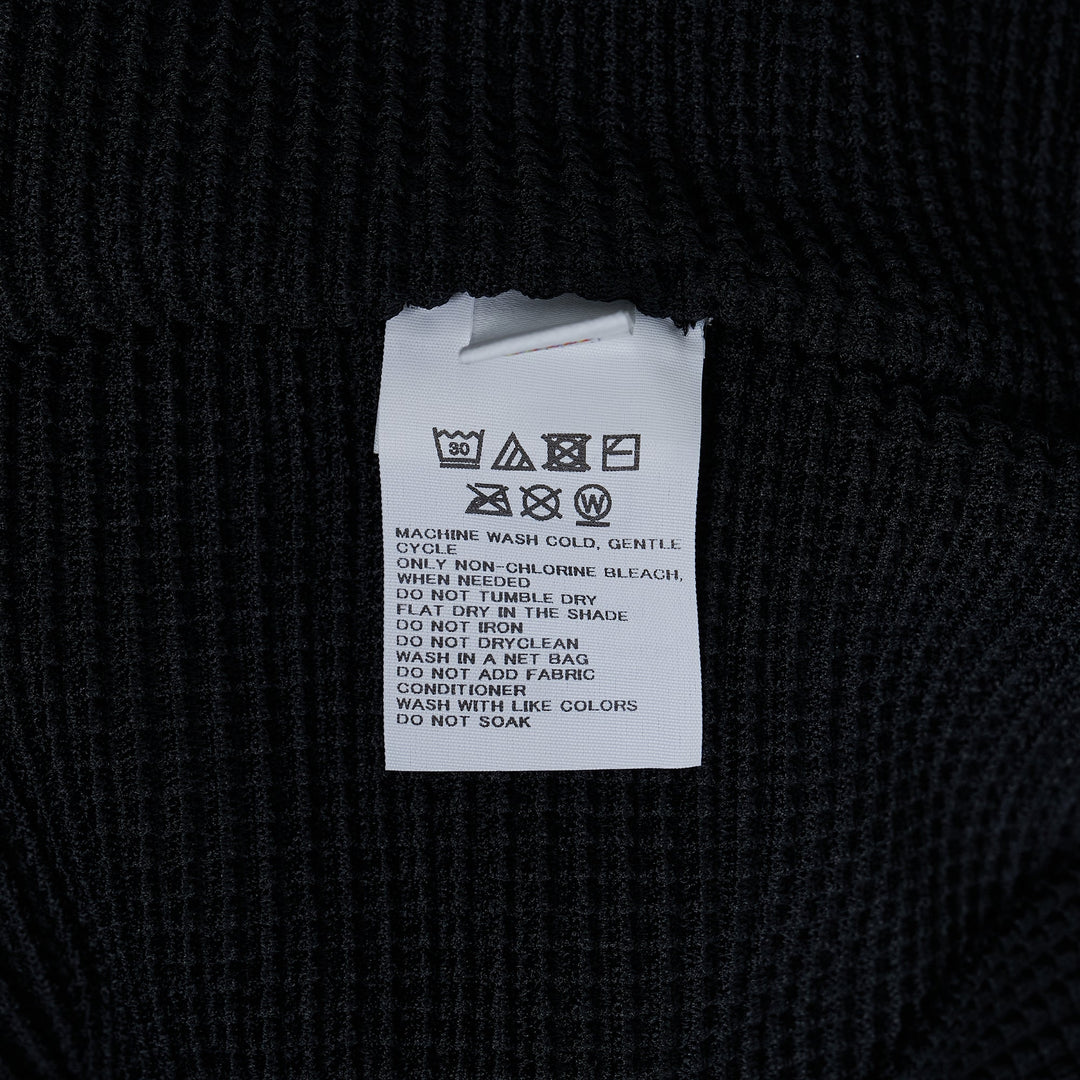 me Issey Miyake Knit Stretch Pleats Top in black, featuring a waffle-grid pleated texture, round neckline, and cap sleeves, displayed flat on a white background.