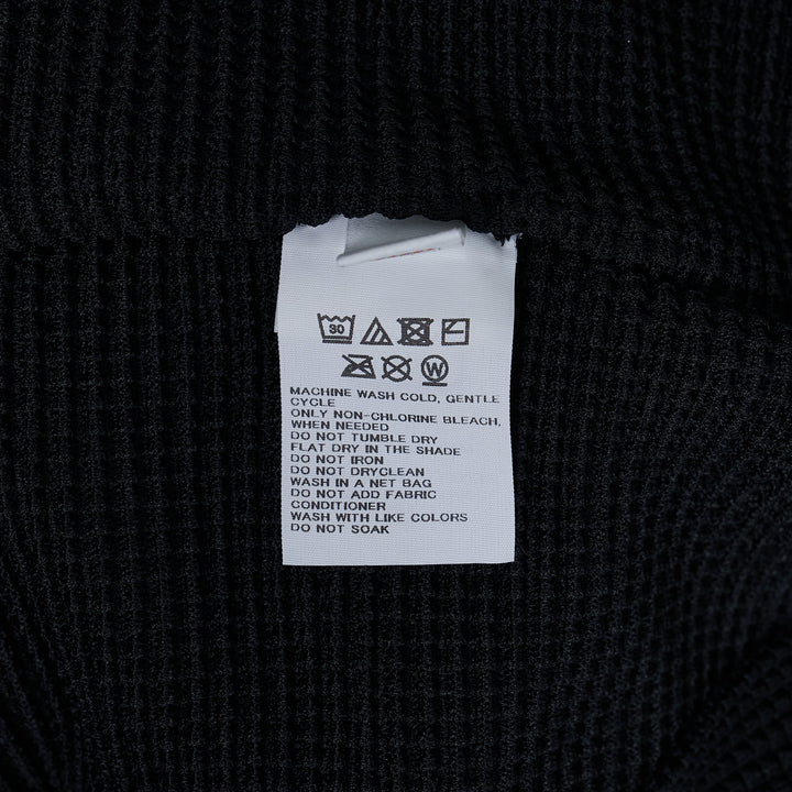 me Issey Miyake Knit Stretch Pleats Top in black, featuring a waffle-grid pleated texture, round neckline, and cap sleeves, displayed flat on a white background.
