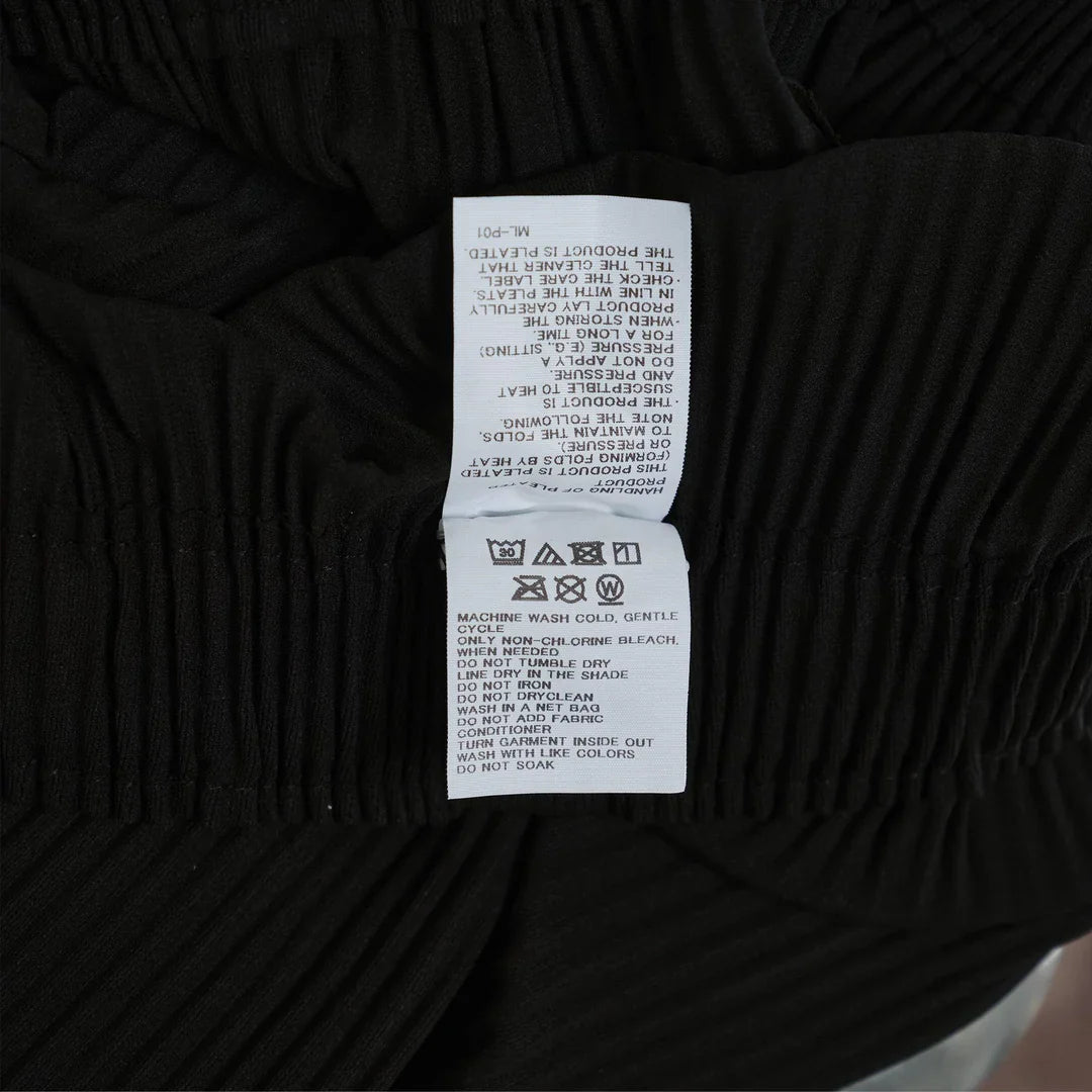 me Issey Miyake Fine Knit Pleats Skirt in black, midi length with vertical pleating and elasticated waistband, flat lay on white background