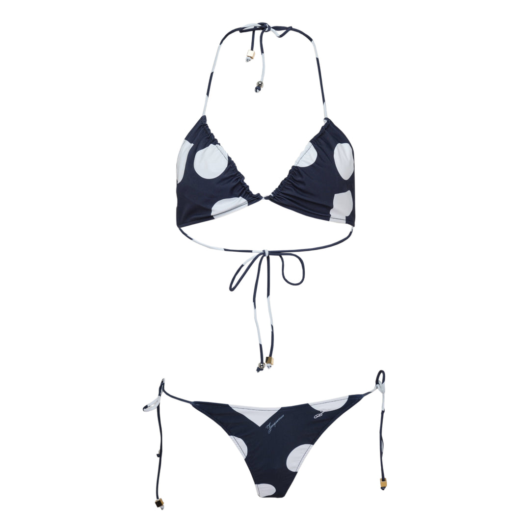 Jacquemus navy and white polka dot triangle bikini set with halter neck tie top and adjustable side-tie bottoms, featuring gold-tone hardware charms