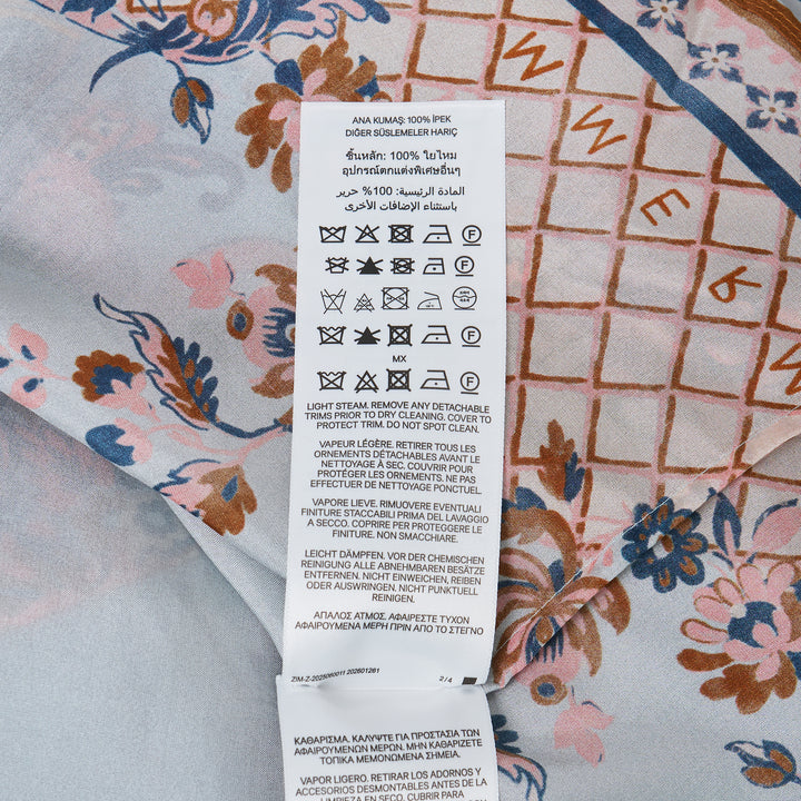 Zimmermann Aster Scarf Midi Skirt in a paisley floral print with coral, navy, and amber tones on a soft blue ground, styled with a draped overlay and side-tie waist