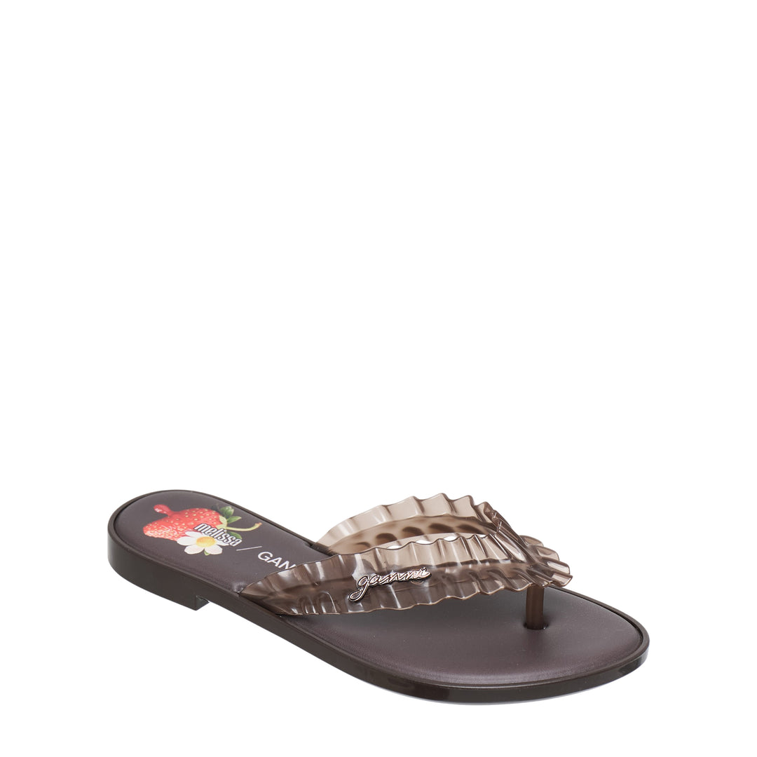 Ganni x Melissa ruffle flip flop sandal in chocolate brown semi-transparent PVC with layered ruffle strap and logo charm at the toe post, flat moulded sole, side profile view