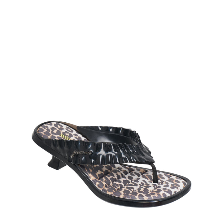 Ganni x Melissa black thong kitten heel sandal with ruched petal-texture strap, gold script logo hardware, leopard-print footbed, and sculptural low heel, shown in profile