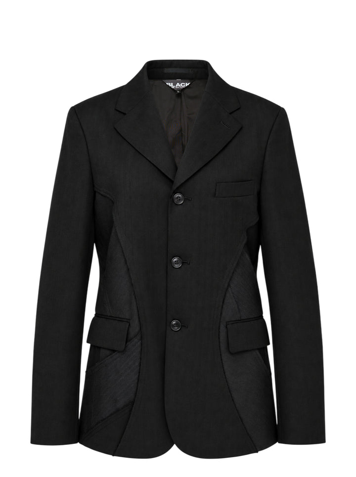 Black single-breasted herringbone tailored jacket with curved patchwork panel inserts, notch lapel and flap pockets by Comme des Garçons Black