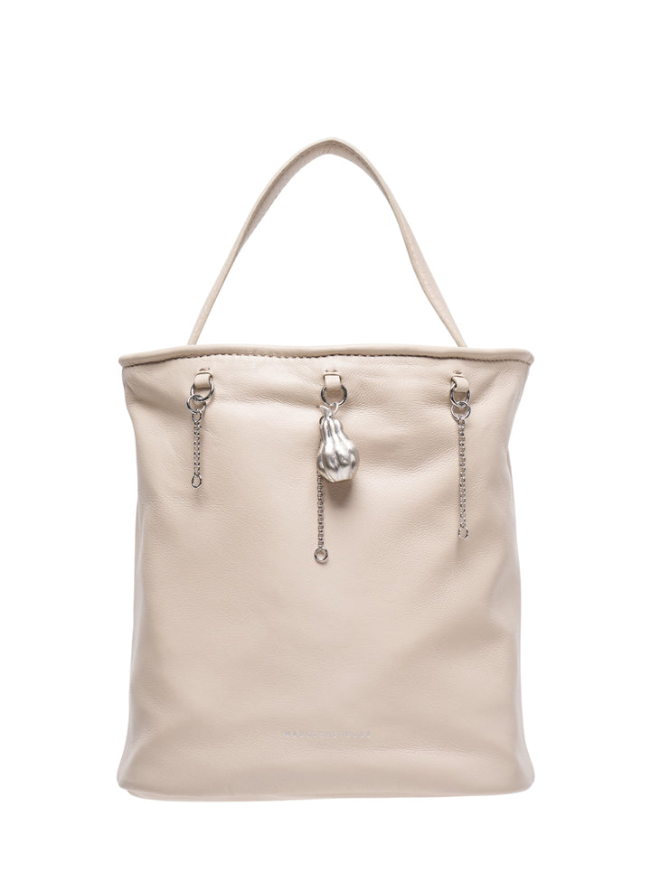 Marge Sherwood Wired Bucket Bag in pebbled cream leather with a single top handle, three silver chain drops, and a sculptural metal charm pendant at centre