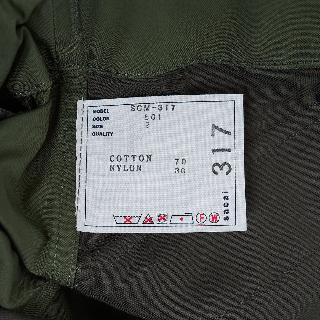 sacai Cotton Nylon Oxford Pants in black, featuring a wide-leg silhouette, integrated belted waist with silver-tone buckle, and cargo side pockets