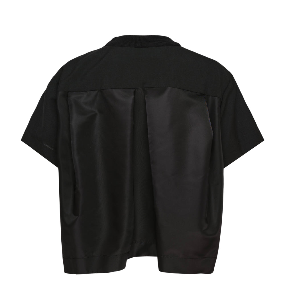 sacai Suiting Pullover Top in black with ribbed zip-detail collar, chest patch pocket, twin cargo pockets, and layered semi-sheer hem — front view