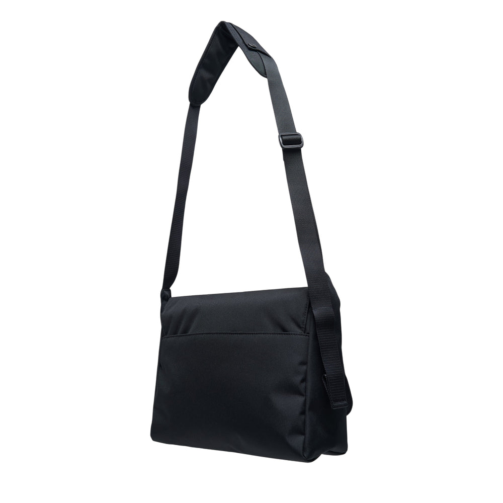 sacai Pocket Shoulder Bag in black nylon with layered front zip pockets, silver zipper hardware, adjustable webbing strap, and woven sacai logo label