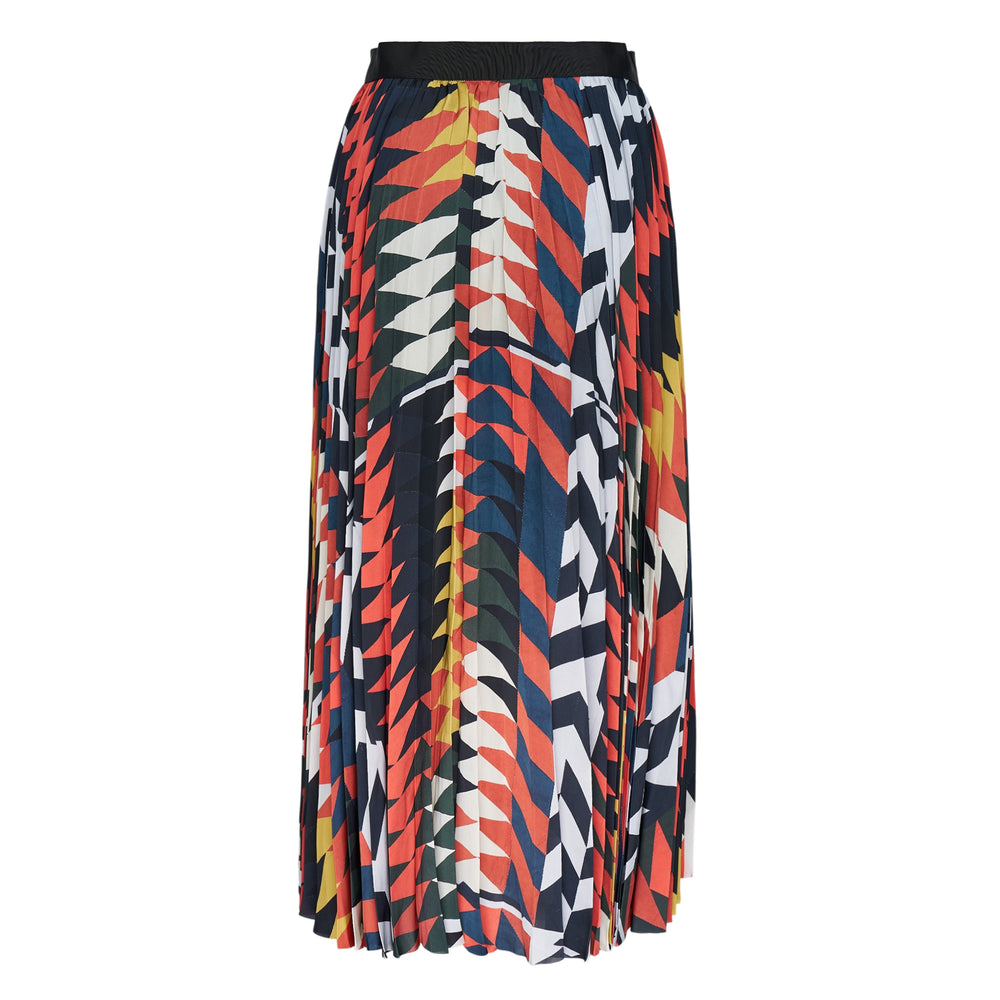 sacai x A.P.C. Quilts pleated midi skirt with bold geometric print in red, navy, white, and yellow, featuring a black waistband with metal buckle and vertical contrast trim
