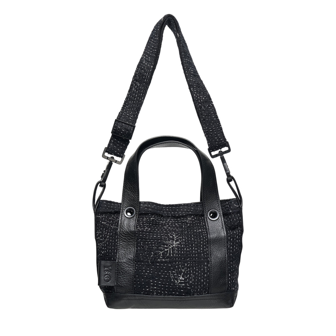 Y's x FAF 008 black kantha-stitched tote bag with pebbled leather trim, dual short handles, and a wide adjustable crossbody strap with gunmetal hardware