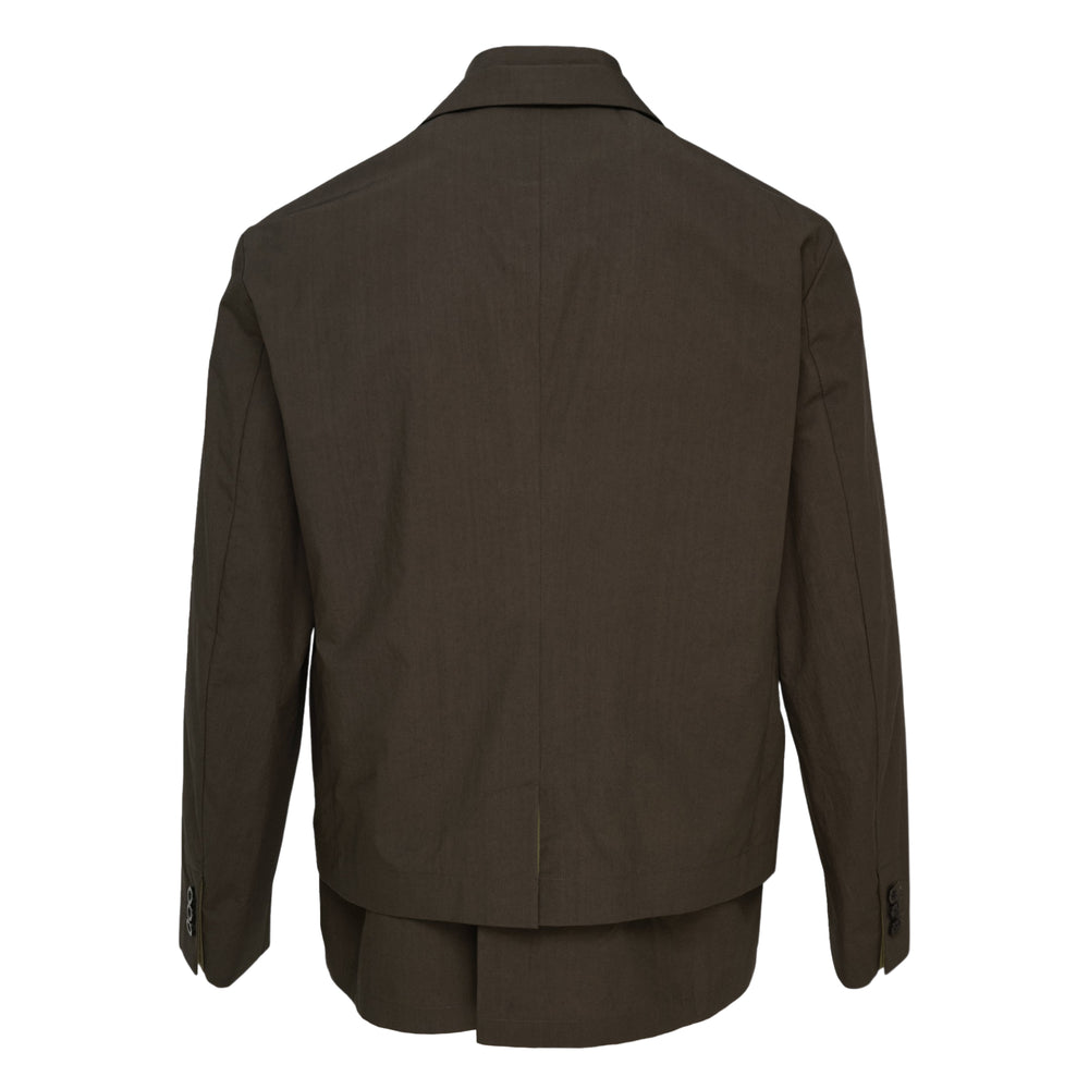sacai Cotton Typewriter Jacket in olive brown, displayed flat, showing a layered blazer-over-shirt construction with notched lapels, black buttons, and flap hip pockets