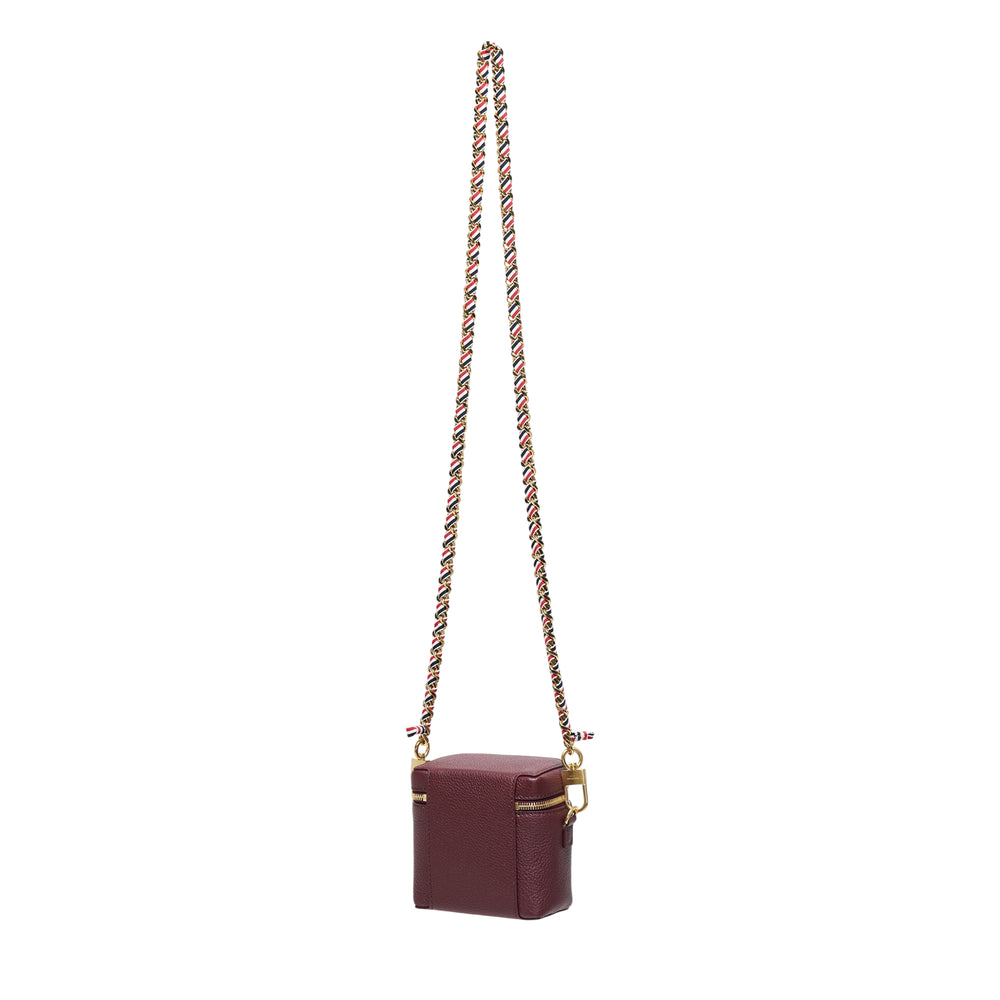 Thom Browne burgundy pebbled leather box pouch with double gold-tone zip closure and long crossbody chain strap featuring red, white, and blue woven ribbon interlaced with gold links