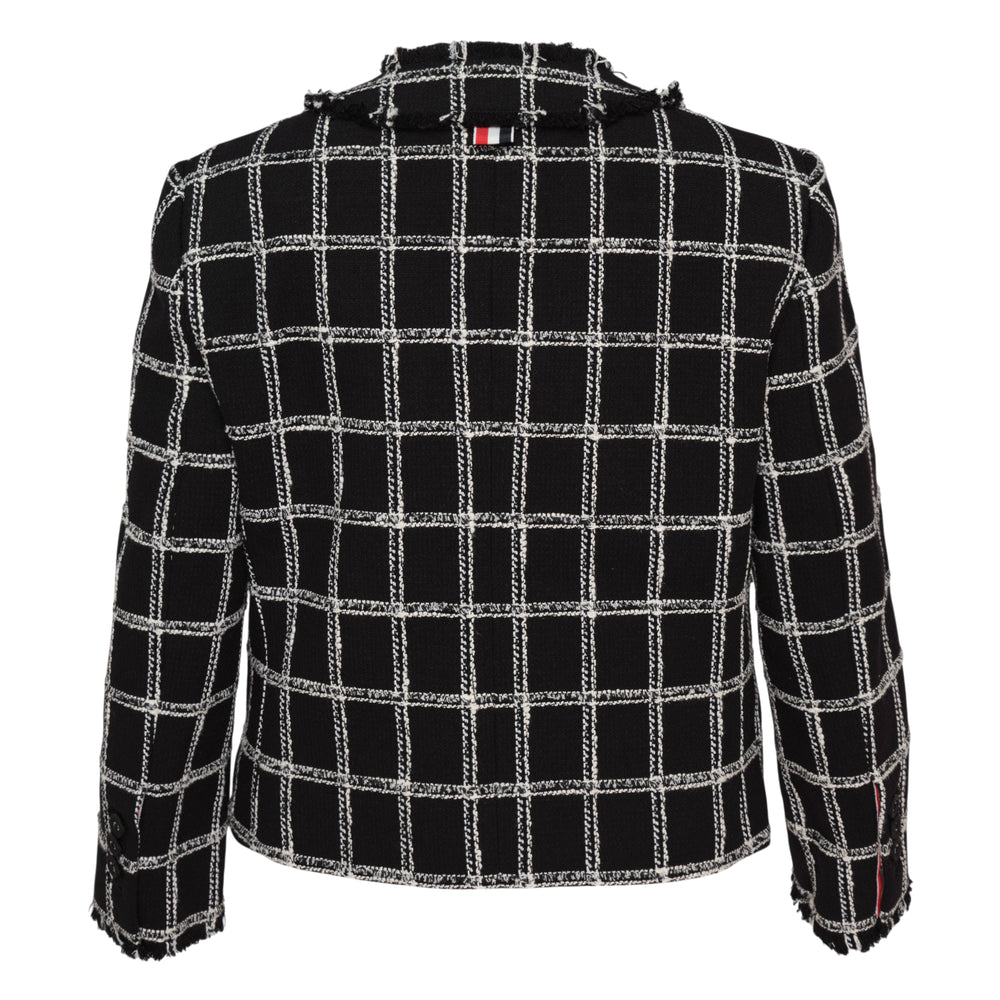 Thom Browne black and white windowpane tweed cardigan jacket with frayed edges, double-breasted button closure, and red, white, and blue striped lining, laid flat on white background